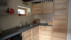 Una cocina con armarios de madera, encimera negra y horno empotrado.