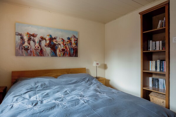 Una camera da letto con un letto grande, una testiera in legno, una libreria e un quadro appeso al muro.