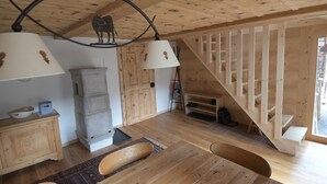 Un interior de madera con una escalera, una mesa de comedor con sillas y una lámpara decorada con una vaca.
