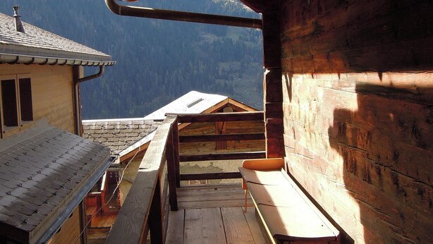 Una cabaña de madera con terraza de madera y vistas a las montañas.