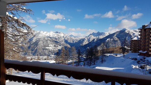 Vistas de la montaña con picos nevados, una estación de esquí y un edificio con balcones.