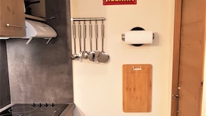 Una cocina compacta con estufa, lavamanos y armarios de madera. Un letrero en la pared dice "RHUM NEGRITA".