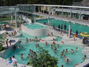 Una gran piscina al aire libre con varias secciones y una zona cubierta de cristal.