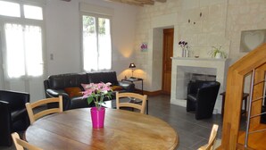 Ein Wohnzimmer mit einem Holztisch, Stühlen, einem schwarzen Ledersofa, einem Kamin und einer Steinwand.