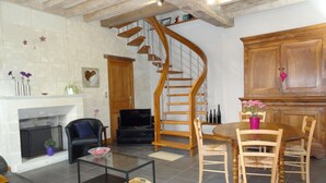 Ein Wohnzimmer mit Kamin, Fernseher, einer Holztreppe und einem Essbereich.