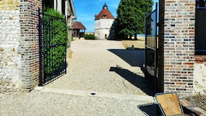 A courtyard with a gravel path leading to a building with a brick facade and a wooden gate. - CHARMING RESIDENCE with swimming pool and indoor spa (Conches-en-Ouche)