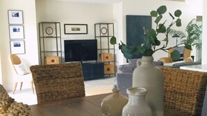 A living room with a dark wood table, wicker chairs, a flat-screen TV, and a ceiling fan. - Put some MAGIC into your vacation.  Disney only 20 minutes away! (Haines City)