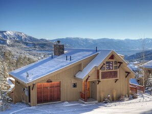 Escape to a serene mountain retreat with a cozy cabin featuring a prominent chimney, large door, and inviting front porch.