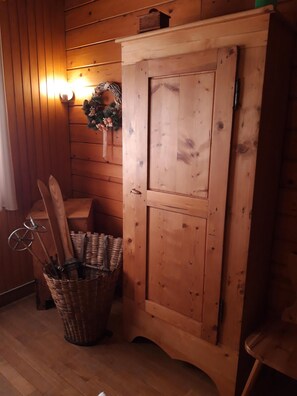 A wooden interior with a wooden cabinet, a wicker basket with skis, and a wall-mounted light fixture. - NOVELTY. Exceptional view, Hérisson waterfalls (Bonlieu)