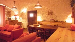 A cozy room with a stone ceiling, a wooden dining table, and a red sofa. - Serre Chevalier Apartment in a house Country, nice amenities. (Saint-Chaffrey)