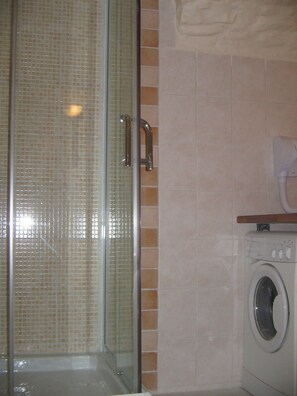 A bathroom with a glass shower enclosure, a washing machine, and a towel dispenser. - Serre Chevalier Apartment in a house Country, nice amenities. (Saint-Chaffrey)