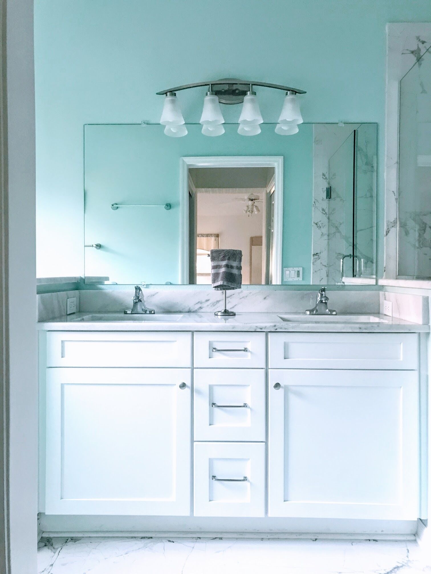 A bathroom with a large mirror, two sinks, and a glass shower enclosure.