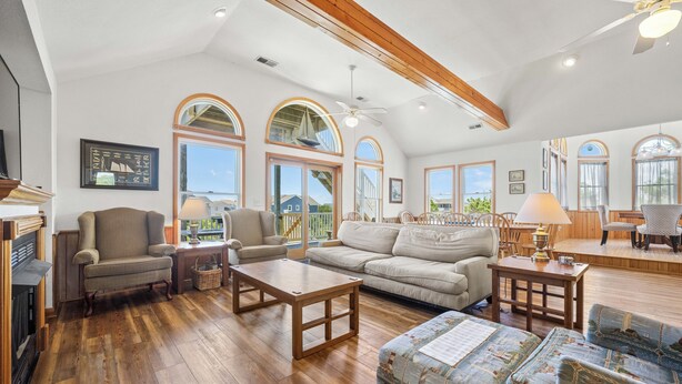 A spacious living room with a wooden floor, a sofa, a coffee table, and a fireplace. - Crazy4Shore: Dog-friendly, Large Private Pool, Hot Tub, 1500 Ft to Beach Access (Corolla)
