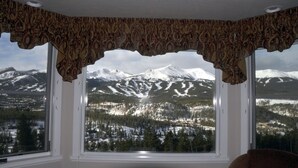 Habitación con un amplio ventanal que da a montañas nevadas y un valle boscoso.