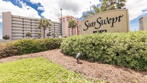 Placa de hotel com o nome 'SunSwept' e um edifício ao fundo.