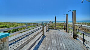 Una passerella di legno conduce a una spiaggia sotto un cielo azzurro limpido.