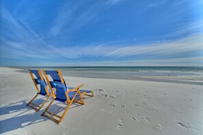 A beach with two blue and yellow beach chairs and footprints in the sand. -   Gated, 80steps to private beach, Short stroll to Rosemary & Alys Beach (Rosemary Beach)