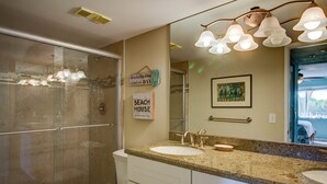 Une salle de bain avec une douche à parois de verre, un lavabo avec un meuble-vasque et un miroir au-dessus du lavabo.
