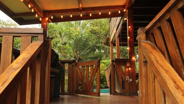 A wooden staircase leading to a covered area with string lights. - Cozy Caribbean Beachfront House (Pet & Kid Friendly) (Puerto Viejo)