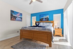 Un dormitorio con una cama de madera, una pared de acento azul y dos cuadros.
