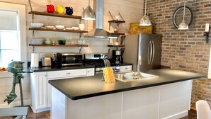 A modern kitchen with white cabinetry, stainless steel appliances, and a black countertop. - STONES THROW RETREAT in Downtown Lewisburg (Lewisburg)