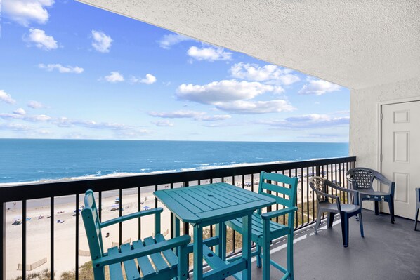 Ein Balkon mit Blick auf Strand und Meer, ausgestattet mit Tisch und Stühlen.