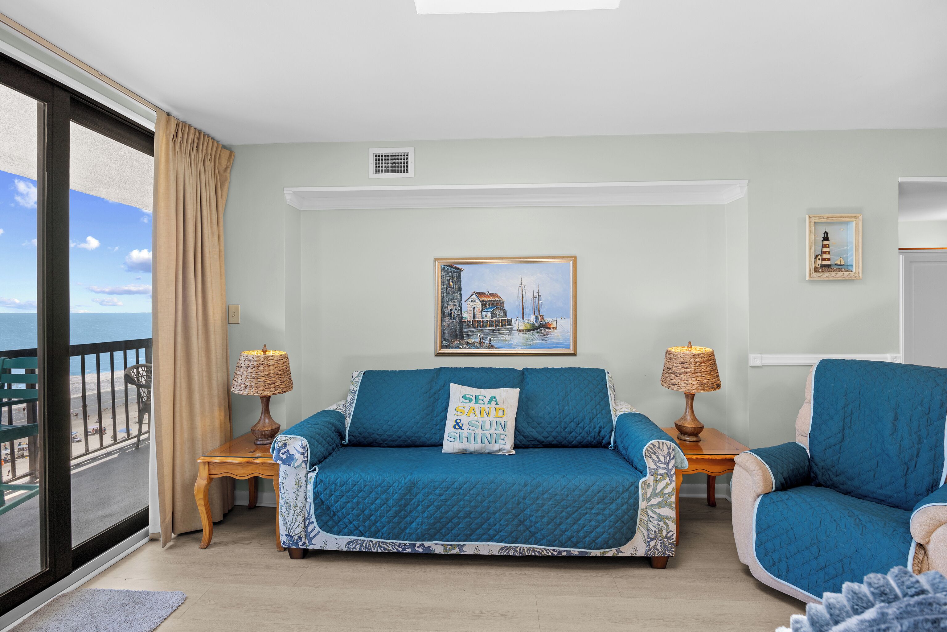 A room with a sofa, armchair, and a painting on the wall.