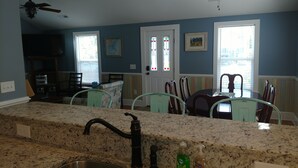 Cozinha com bancadas de granito, pia, ventilador de teto e área de jantar com cadeiras e mesa.