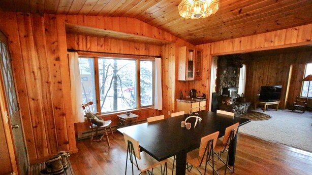 Un interno in legno con un tavolo da pranzo, sedie, un caminetto e un televisore.