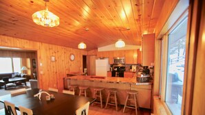 Un interno in legno con cucina, zona pranzo e ampie finestre.