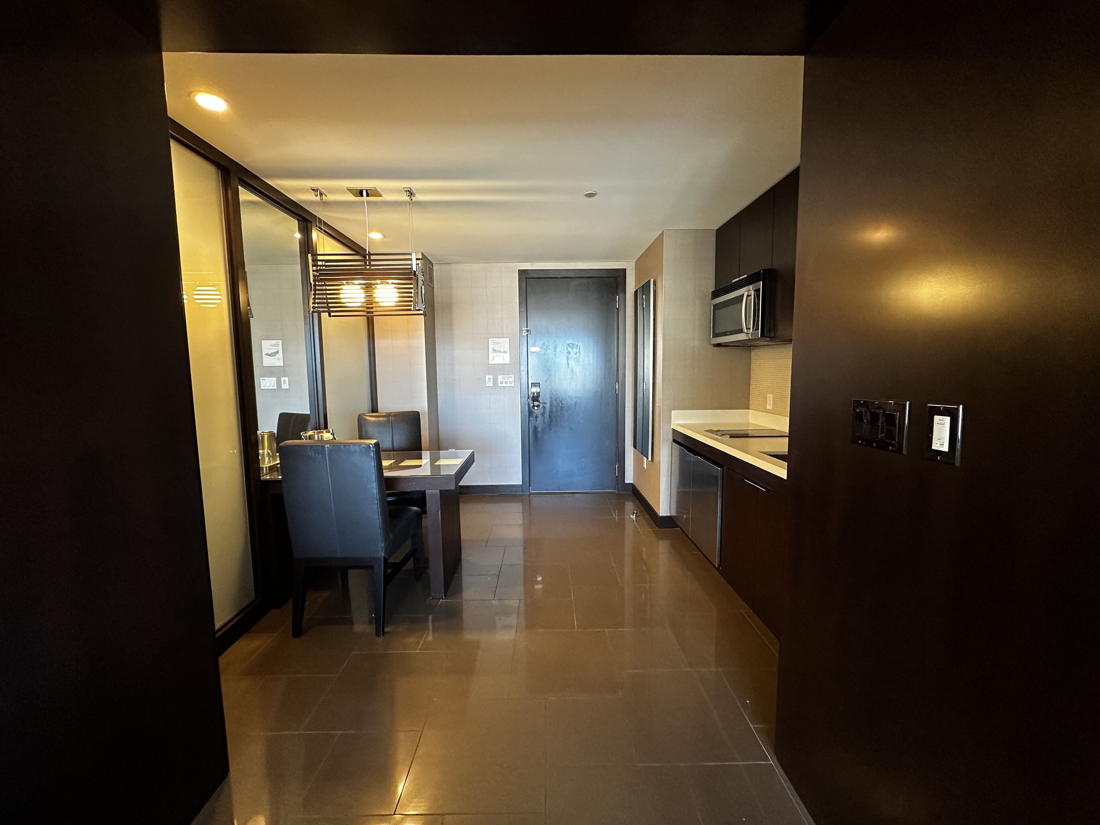 A modern kitchen with a microwave, a sink, and a dining area with a table and chairs.
