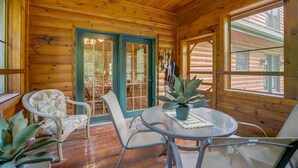 L’intérieur d’un chalet en bois, avec une table ronde en verre, deux chaises et une plante en pot.