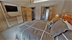 Una camera da letto con un letto grande, un armadio in legno e un televisore montato a parete.