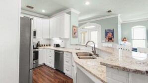 A modern kitchen with white cabinets, stainless steel appliances, and a granite countertop. - Great beach house with access to pools and restaurants.
 (Miramar Beach)