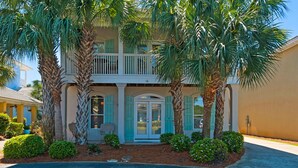 A two-story house with a balcony, palm trees, and a well-maintained front yard. - Great beach house with access to pools and restaurants.
 (Miramar Beach)