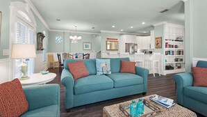 A spacious living room with teal sofas, a coffee table, and a bookshelf. - Great beach house with access to pools and restaurants.
 (Miramar Beach)