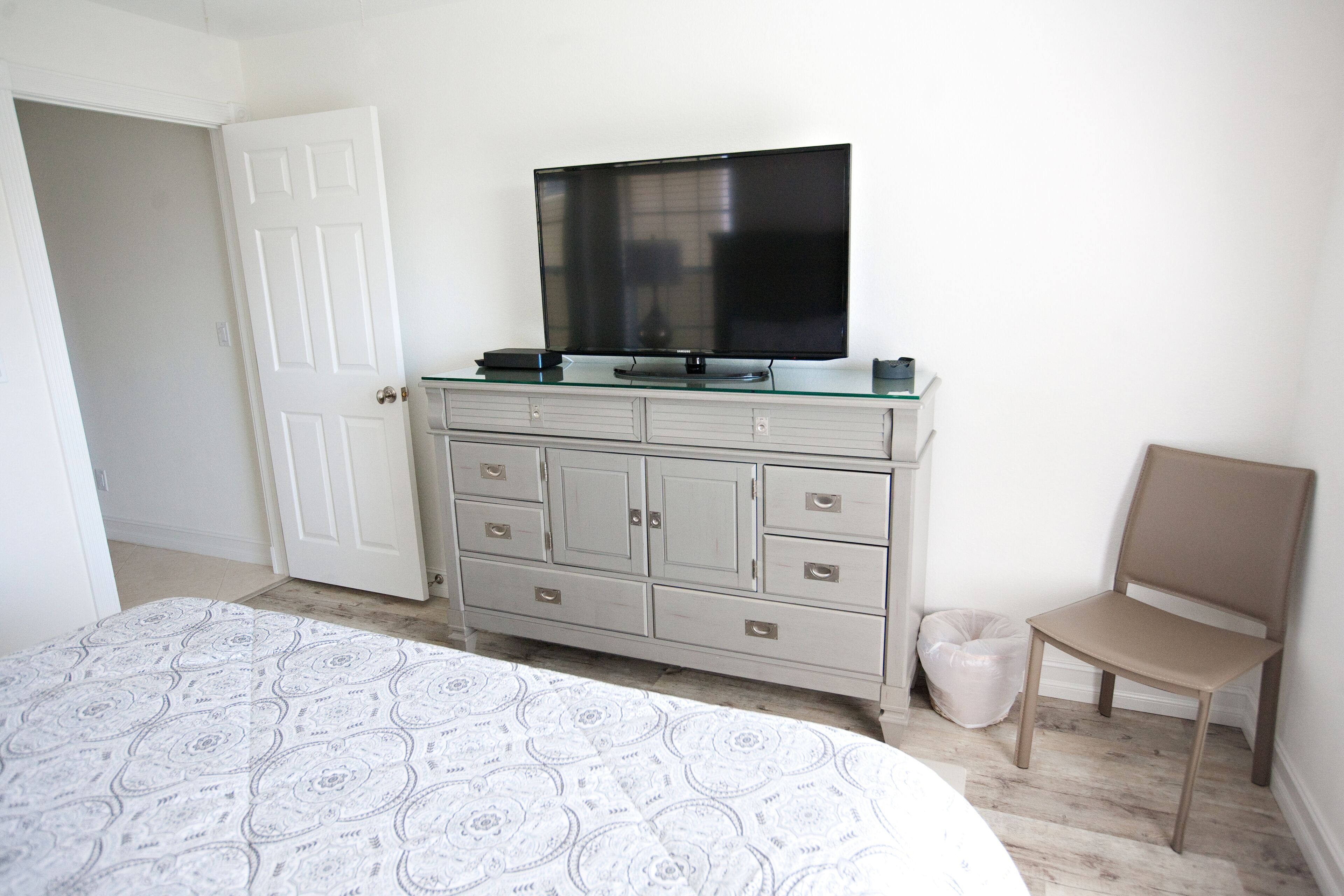 Een slaapkamer met een bed, een dressoir, een televisie en een stoel.