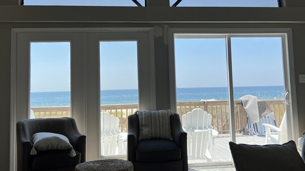 A spacious room with large windows overlooking a beach, furnished with two armchairs, a sofa, and a small table. - Relax With Walls Of Windows Directly On The Gulf! (Gulf Shores)