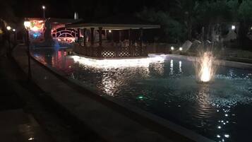 Relax by the serene pool, surrounded by a tranquil ambiance and a shaded gazebo.