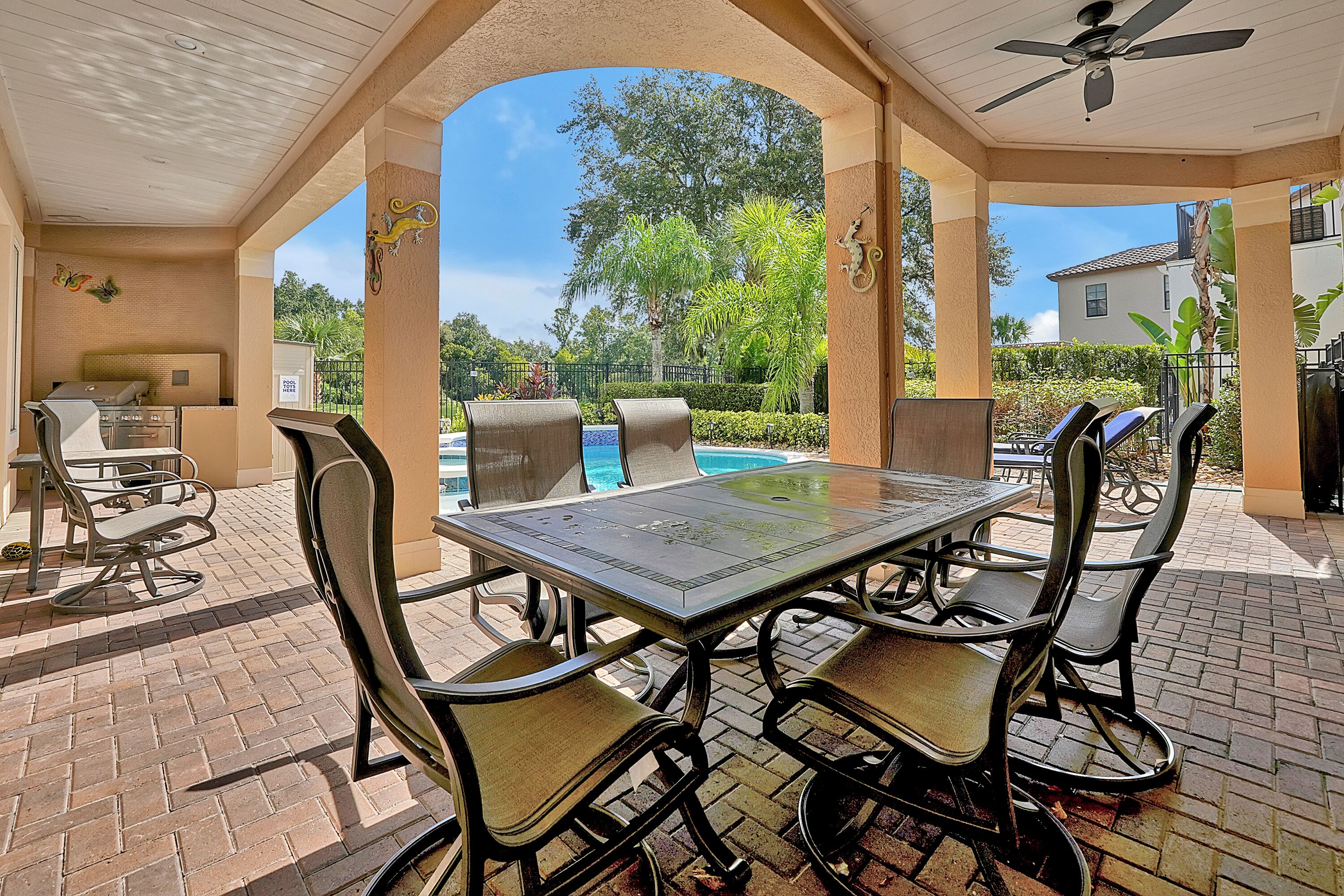 An outdoor patio with a pool table, chairs, and a ceiling fan.