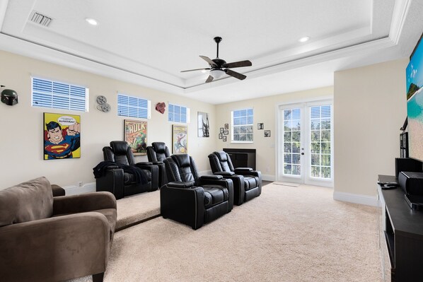 A spacious living room with a ceiling fan, black leather recliners, a brown sofa, and a fireplace. - 🏝️Quiet Private Setting-Theatre & Game Room, large Pool (Kissimmee)