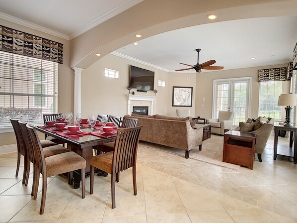 A spacious living area with a dining table set for six, a sofa, a coffee table, and a ceiling fan. - 🏝️Quiet Private Setting-Theatre & Game Room, large Pool (Kissimmee)