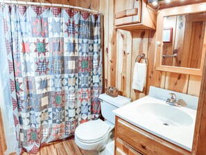 A bathroom with a wooden wall, a white sink, and a toilet.