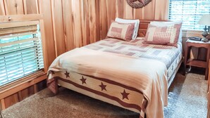 Una habitación de madera con cama, una decoración de estrellas y una ventana con persianas.