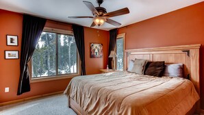 A bedroom with a large bed, a ceiling fan, a window with curtains, and a painting on the wall. - Hot Tub, Mtn Views & Seclusion - Moose Wetlands, 24mi Breck, Pets OK (Fairplay)