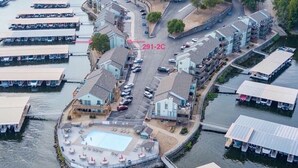 Eine Vogelperspektive auf ein Anwesen am Wasser mit mehreren Booten, die an einem Steg festgemacht sind, einem Schwimmbad und einem Parkplatz.