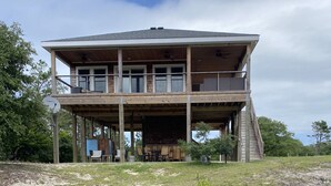 A two-story wooden house with a covered patio and a view of a body of water.