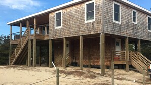 A two-story building with a wooden exterior, a covered porch, and a staircase leading to the upper level.