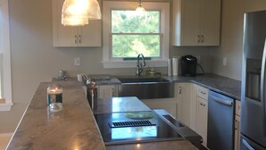 A modern kitchen with a central island, stainless steel appliances, white cabinetry, and pendant lighting.
