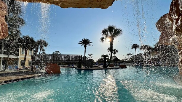 A pool area with clear water, palm trees, and a rock formation. - HangLoose14AD-Beautiful Beach Cottage@ the Purple Parrot Resort/Perdido Key FL (Pensacola)